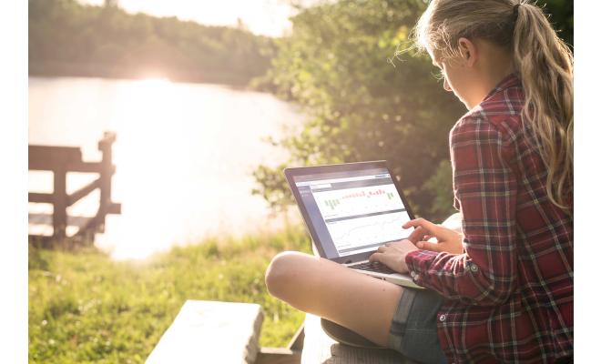 Woman by lake looking at data on software