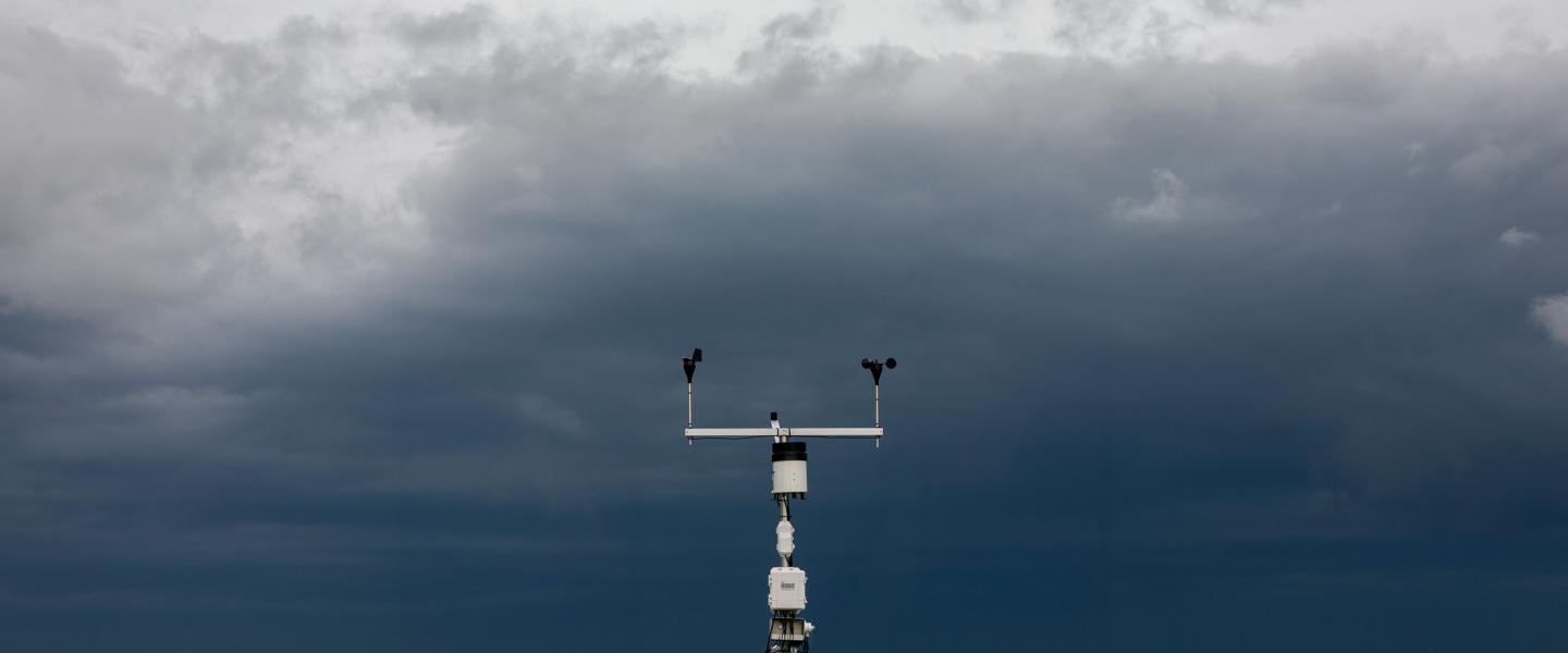 weather station monitors conditions under dark storm clouds in field