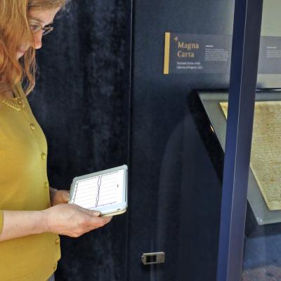 Woman observing the Magna Carta exhibit with iPad